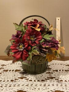 Fall faux floral arrangement in green basket with handle.