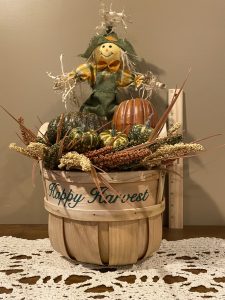 Fall arrangement with pumpkins and scarecrow in Happy Harvest basket.